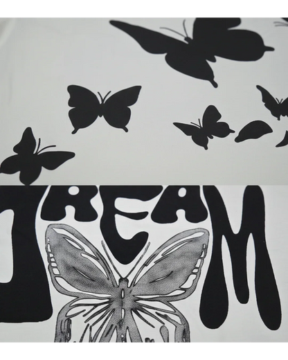 Close-up of white streetwear fabric with black butterfly prints and bold 'DREAM' lettering.
